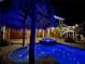 Night view of a sparkling pool with a tiki bar and hot tub at 262 Banana Rd, Palm Harbor, FL 34683