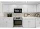 White kitchen with stainless steel appliances and wood flooring at 3111 E Vina Del Mar Blvd, St Pete Beach, FL 33706