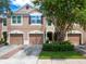 Tan three-unit townhouse with garages and landscaping at 26607 Chimney Spire Ln, Wesley Chapel, FL 33544
