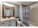 Bathroom with tub, shower, gray patterned curtain, and wooden framed mirror at 26607 Chimney Spire Ln, Wesley Chapel, FL 33544