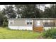 Tan mobile home with wooden steps and porch, in the rain at 6812 Woodsman Dr, Wesley Chapel, FL 33544