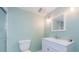 Bathroom featuring mint-green walls, standard toilet, shower, white vanity, and a standard mirror with lighting at 5455 Lake Le Clare Rd, Lutz, FL 33558