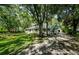 Expansive property featuring a large house with a wraparound porch and a long driveway lined with mature trees at 5455 Lake Le Clare Rd, Lutz, FL 33558
