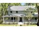 Charming two-story home featuring a welcoming front porch with hanging plants and manicured landscaping at 5455 Lake Le Clare Rd, Lutz, FL 33558