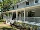 Side view of a wraparound porch featuring decorative hanging fern baskets, and meticulously maintained landscaping at 5455 Lake Le Clare Rd, Lutz, FL 33558