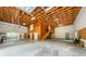 Large garage featuring high ceilings with exposed wood beams, concrete flooring, and multiple access doors at 5455 Lake Le Clare Rd, Lutz, FL 33558