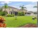 Spacious backyard showcasing well-maintained lawn, mature landscaping, and outdoor living spaces with a white picket fence at 7127 Forest Mere Dr, Riverview, FL 33578