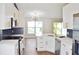 Bright kitchen with white cabinets, gold hardware, blue backsplash, quartz countertops, and stainless steel appliances at 26933 Carmen Pl, Lutz, FL 33559