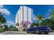 Modern high-rise condominium building with balconies, a blue convertible, and tropical landscaping on a sunny day at 5701 Bowen Daniel Dr. # 504, Tampa, FL 33616