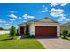 Charming single-story home with a well-maintained lawn, paver driveway, and a lovely red two-car garage door at 11883 Brighton Knoll Loop, Riverview, FL 33579