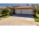 Three-car garage with herringbone driveway and landscaping at 4977 Sapphire Sound Dr, Wimauma, FL 33598