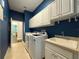 Bright laundry room with white cabinets, a utility sink, and built-in shelving at 4977 Sapphire Sound Dr, Wimauma, FL 33598