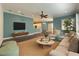 A comfortable living room featuring hardwood floors, neutral decor, and a ceiling fan, with views into the kitchen at 4977 Sapphire Sound Dr, Wimauma, FL 33598