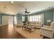 A comfortable living room with hardwood floors, plenty of seating and natural light with a ceiling fan at 4977 Sapphire Sound Dr, Wimauma, FL 33598