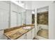 Bright bathroom with tiled counter, white cabinets, and large mirror reflecting shower and entry door at 5608 Pinnacle Heights Cir # 305, Tampa, FL 33624