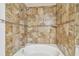 Close-up of bathtub with a decorative brown tiled shower, accented with a chrome shower head at 5608 Pinnacle Heights Cir # 305, Tampa, FL 33624