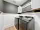 Modern laundry room with white cabinets, wood floors, and stainless steel washer and dryer at 11828 Ranchers Gap Dr, Odessa, FL 33556