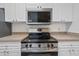 Stainless steel range and microwave in a kitchen with white cabinets at 18001 Richmond Place Dr # 511, Tampa, FL 33647