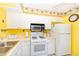White kitchen with yellow walls and appliances at 1619 Mission Hills Blvd, Clearwater, FL 33759