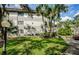 Exterior view of a condo building with lush landscaping and palm trees at 2650 Countryside Blvd # F110, Clearwater, FL 33761
