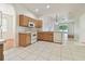 Bright kitchen featuring white appliances, wood cabinets, tile floors, and a view into the living area at 3232 Gianna Way, Land O Lakes, FL 34638