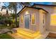 Well-lit home's front exterior features a blue door and step lighting for evening curb appeal at 6907 N 20Th St, Tampa, FL 33610