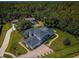 Overhead view of a gray home with a screened-in pool and a long driveway on a lush green lawn at 180 Keystone Palms Blvd, Tarpon Springs, FL 34688