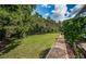 Lush backyard with green grass, trees, and a brick-paved walkway adding natural beauty to the property at 180 Keystone Palms Blvd, Tarpon Springs, FL 34688