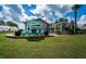 Spacious backyard with lush green grass, blue chairs, patio, and view of the screened-in pool area at 180 Keystone Palms Blvd, Tarpon Springs, FL 34688