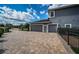 Paver driveway leading to an attached two-car garage on a gray house at 180 Keystone Palms Blvd, Tarpon Springs, FL 34688