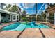 View of pool area in screened enclosure with attached spa, seating area, and lush landscaping at 180 Keystone Palms Blvd, Tarpon Springs, FL 34688