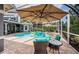 Relaxing screened pool area featuring an umbrella-shaded table and chairs, ideal for outdoor gatherings at 180 Keystone Palms Blvd, Tarpon Springs, FL 34688