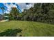 Green lawn with home view, trees, and partial fence in background at 180 Keystone Palms Blvd, Tarpon Springs, FL 34688