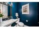 Elegant powder room with dark blue walls, white vanity, and gold accents at 180 Keystone Palms Blvd, Tarpon Springs, FL 34688