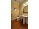 Classic powder room with pedestal sink, hardwood floors, and framed mirror at 29731 Chapel Park Dr, Wesley Chapel, FL 33543