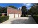 Three-car brick garage with white doors and landscaping at 29731 Chapel Park Dr, Wesley Chapel, FL 33543