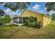 Landscaped backyard with a yellow house and screened patio at 1122 Vinetree Dr, Brandon, FL 33510