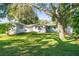 Wide shot of the backyard showing the layout of the house, yard and trees at 5824 11Th St, Zephyrhills, FL 33542