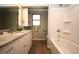 Bright bathroom featuring a full tub with white wall surround, vanity with stone countertop, and modern cabinets at 5824 11Th St, Zephyrhills, FL 33542