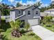Two-story house with gray siding, white garage door, and landscaping at 6267 Back Forty Loop, Zephyrhills, FL 33541