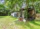 View of sheds and a simple greenhouse amidst lush greenery and natural light in the backyard at 26831 Chianina Dr, Wesley Chapel, FL 33544