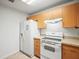 White appliances and light wood cabinets in this galley kitchen at 26831 Chianina Dr, Wesley Chapel, FL 33544