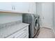 Laundry room with granite countertop, white cabinets, and modern appliances at 717 Manns Harbor Dr, Apollo Beach, FL 33572