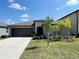 Single-story home with a two-car garage and landscaped lawn at 10411 Alder Green Dr, Riverview, FL 33578