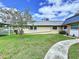 Charming single-story home with a well-maintained lawn and mature tree under a bright blue partly cloudy sky at 11920 Boynton Ln # 11920, New Port Richey, FL 34654