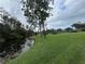 Picturesque waterfront view with lush green grass, mature trees, and a serene stream at 11920 Boynton Ln # 11920, New Port Richey, FL 34654