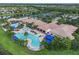 An aerial view highlighting a well-kept community clubhouse, a pool, mature trees, and green spaces at 15911 Cobble Mill Dr, Wimauma, FL 33598