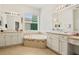 Bright bathroom with dual vanities and a soaking tub with tile surround at 15911 Cobble Mill Dr, Wimauma, FL 33598