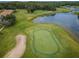 Aerial view of a pristine green and sand trap with a tranquil lake backdrop on a well-maintained golf course at 4350 Live Oak Blvd, Palm Harbor, FL 34685