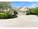 Three-car garage with circular driveway and tropical landscaping at 8945 Magnolia Chase Cir, Tampa, FL 33647